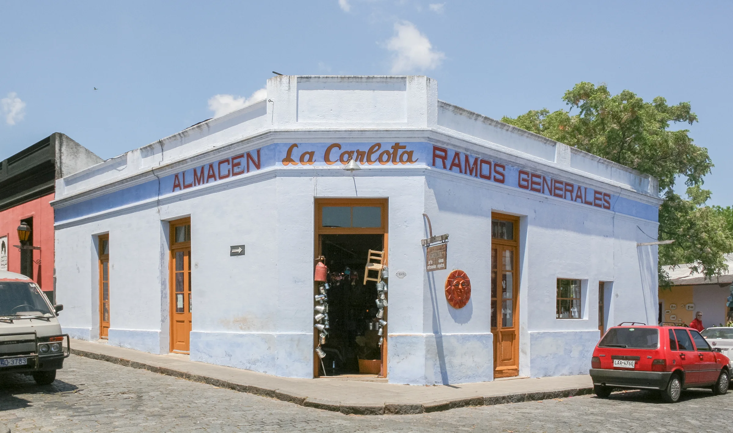 The pale facade of Almacén La Carlota on a street corner in Colonia del Sacramento